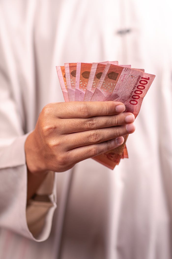 Close-up of a hand holding Indonesian Rupiah banknotes, symbolizing finance and currency exchange.